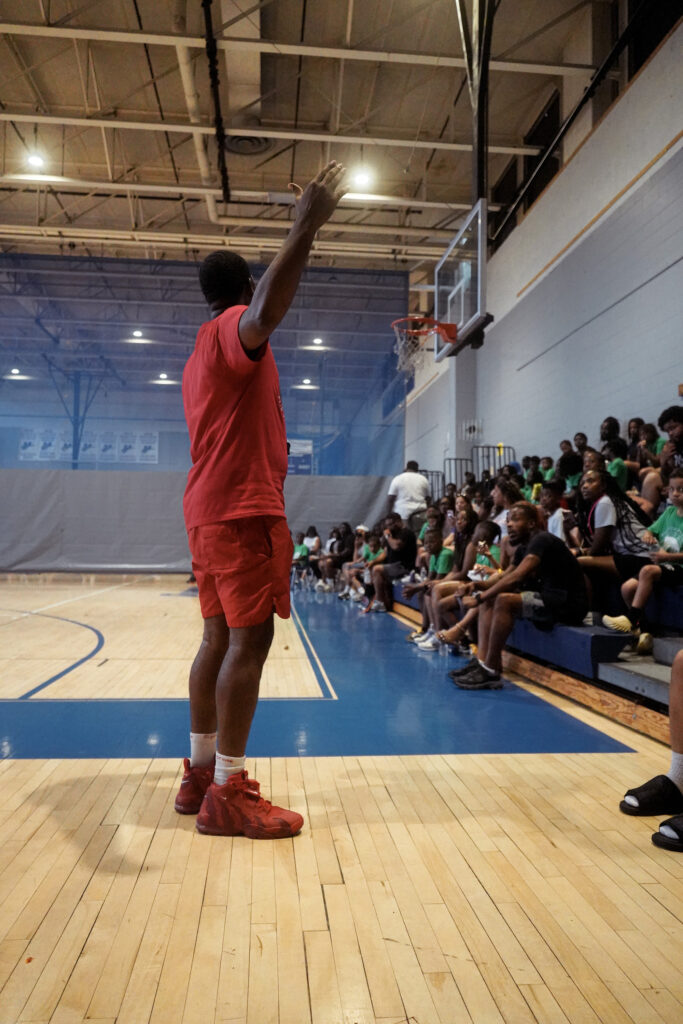 ODAAP leader speaking to children seated on gymnasium bleachers