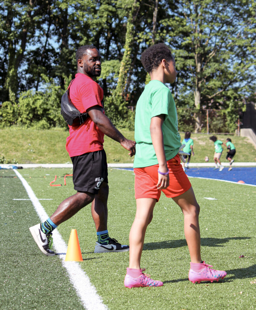 ODAAP leader walking with young male student on football field