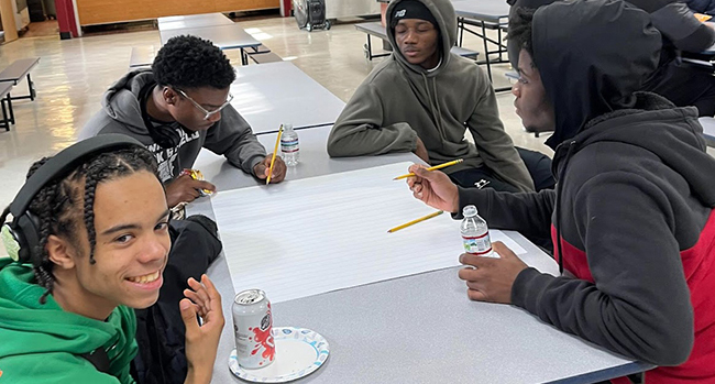 Four teenage boys sitting at cafeteria lunch table
