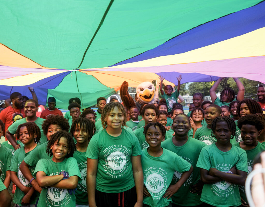 Group of children under a parachute with the Philadelphia Eagles mascot